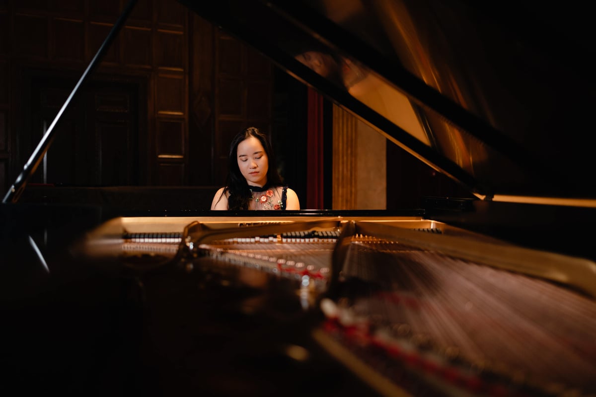 Musician portrait for a pianist taken in a concert hall with a piano and studio lighting.